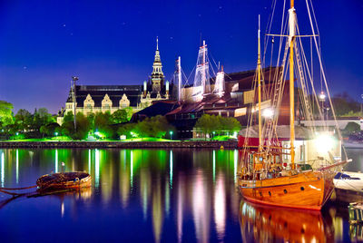 Boats moored at illuminated temple against sky at night