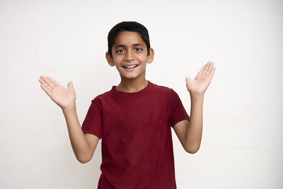 Portrait of smiling boy standing against white background