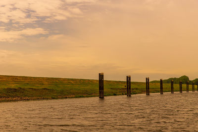 Wooden posts on field against sky during sunset