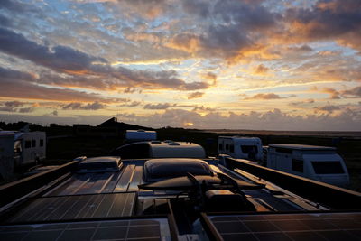 Cars on building against sky during sunset