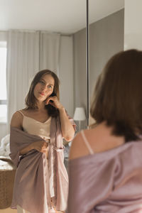 Young woman looking at mirror at home