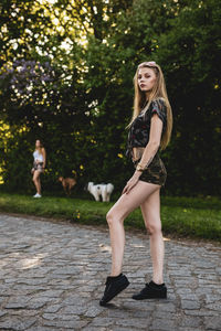 Portrait of beautiful woman standing on footpath with friend in background