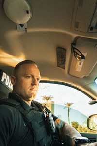 Vertical image low angle shot of of white male caucasian police officer sitting inside a cop vehicle