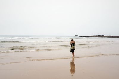 Full length of man walking on beach against clear sky