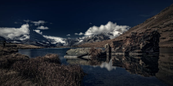 Scenic view of lake by snowcapped mountains against sky