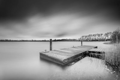 Pier over lake against sky during sunset