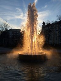 Fountain in city against sky