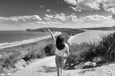 Rear view of woman on beach against sky