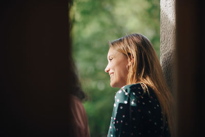 Smiling young woman in balcony looking away during party