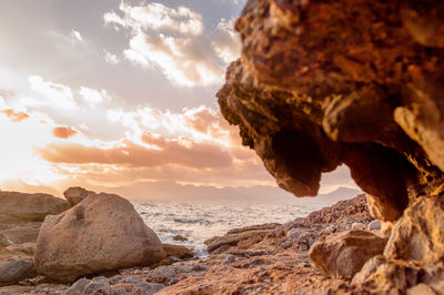 Rock formation on beach against sky during sunset