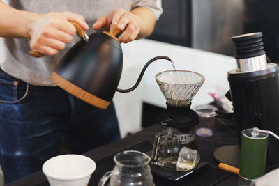 Barista pour hot water on rough brown bubbles coffee through drip filter