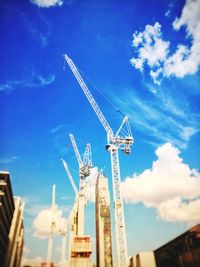 Low angle view of cranes against blue sky