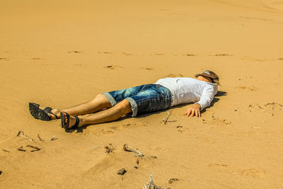 Full length of man lying on sand at beach