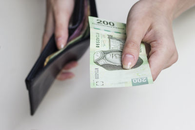 Close-up of hand holding paper over white background