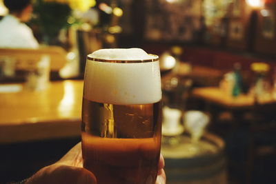 Cropped hand having beer in glass at bar