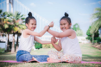 Angry sisters fighting while sitting on yoga mat at park