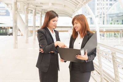 Young woman using phone while standing in office