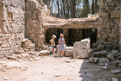 Kids sibling girl and boy travelers travel and explore the ancient excavations of the ruins