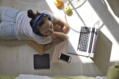 Young woman lying at the window at home with laptop