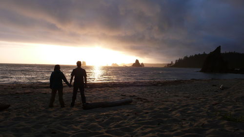 Silhouette people on beach against sky during sunset