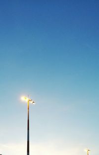 Low angle view of illuminated floodlights against blue sky