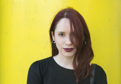 Portrait of smiling young woman against yellow wall