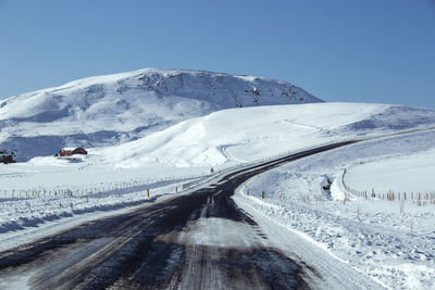 Snowy and slippery road with volcanic mountains in wintertime, iceland