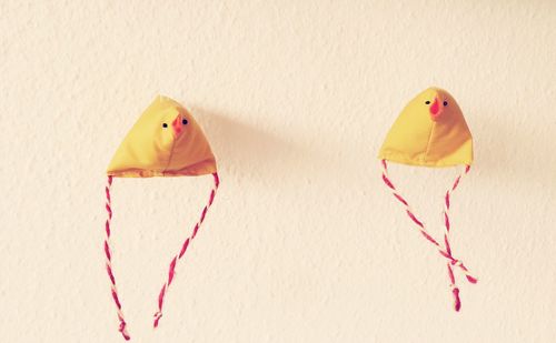 Artificial bird decoration made of yellow fabric hanging against wall