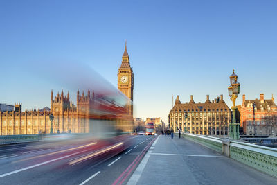 Double-decker bus passes on westminster bridge, in front of westminster palace and clock tower of big ben (elizabeth tower), london, england, united kingdom