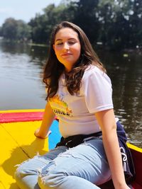 Portrait of young woman sitting by lake