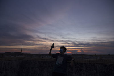 Man standing against orange sky