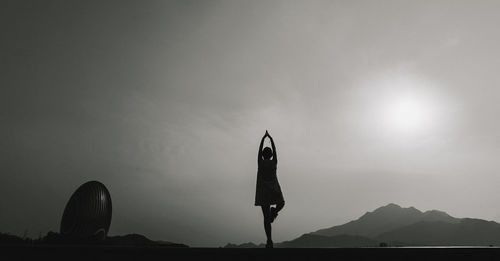 Silhouette woman standing in front of mountain against sky