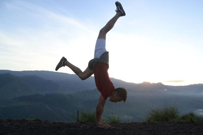 Full length of man doing handstand on mountain