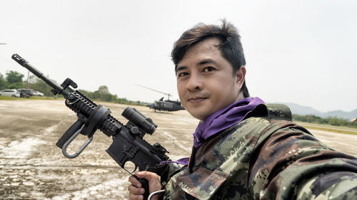 Portrait of army soldier with gun standing at air base 