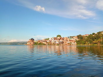 Scenic view of river by buildings against sky