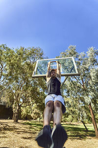 Low angle view of man hanging from basketball hoop