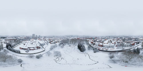 High angle view of snow covered buildings in city against sky