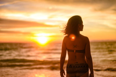 Rear view of man looking at sea during sunset