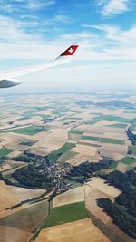 Airplane flying over agricultural field against sky