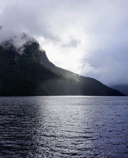 Scenic view of sea by mountains against sky