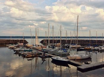 Sailboats in sea against cloudy sky