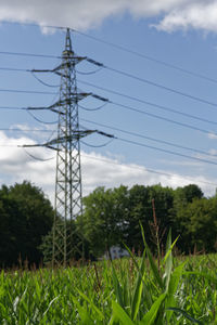 Electricity pylon on field against sky