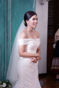 Smiling young woman standing in wedding dress