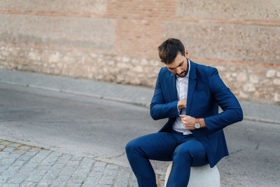 Young man sitting on wall