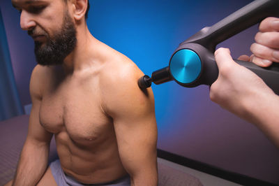 Massage therapist giving shock massage to man in gym