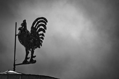 Low angle view of weather vane against sky