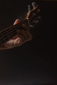 Man playing guitar against black background