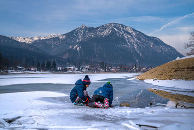 Man with dog on snowcapped mountain against sky