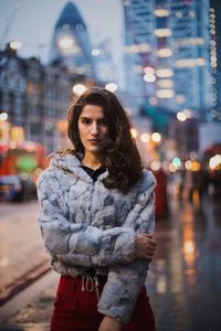 Portrait of woman wearing jacket standing on street in city