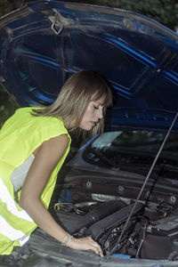 Woman  near a parked broken down car having trouble with her vehicle. waiting for help besides auto